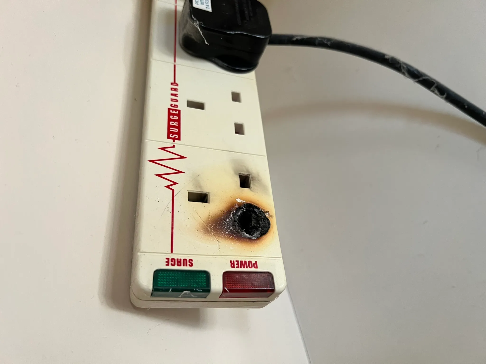 An extension lead with visible burn damage around one socket