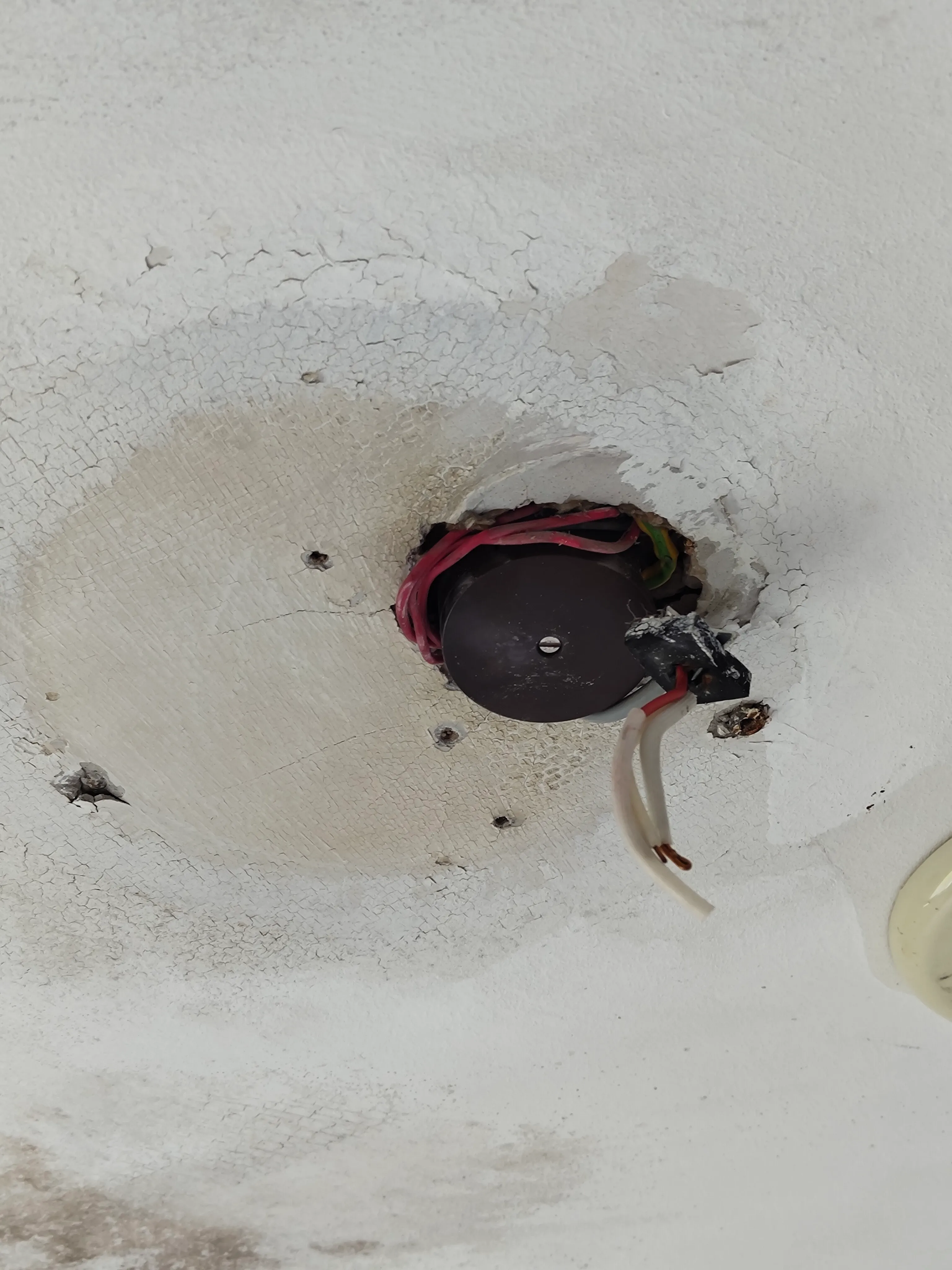 Ceiling opening with a round junction box, taped wiring and a bare copper wire end