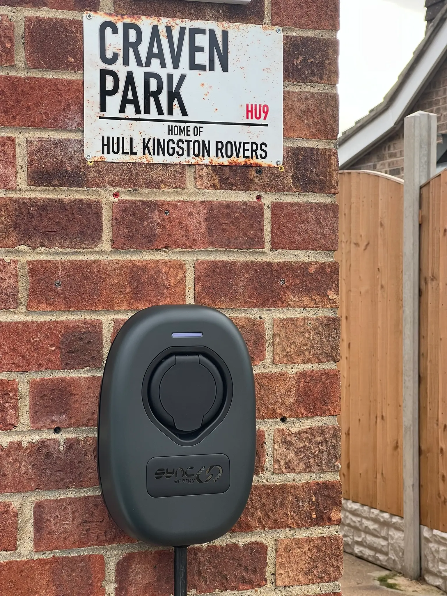 Black EV charging point fitted to a brick wall by John Day Services