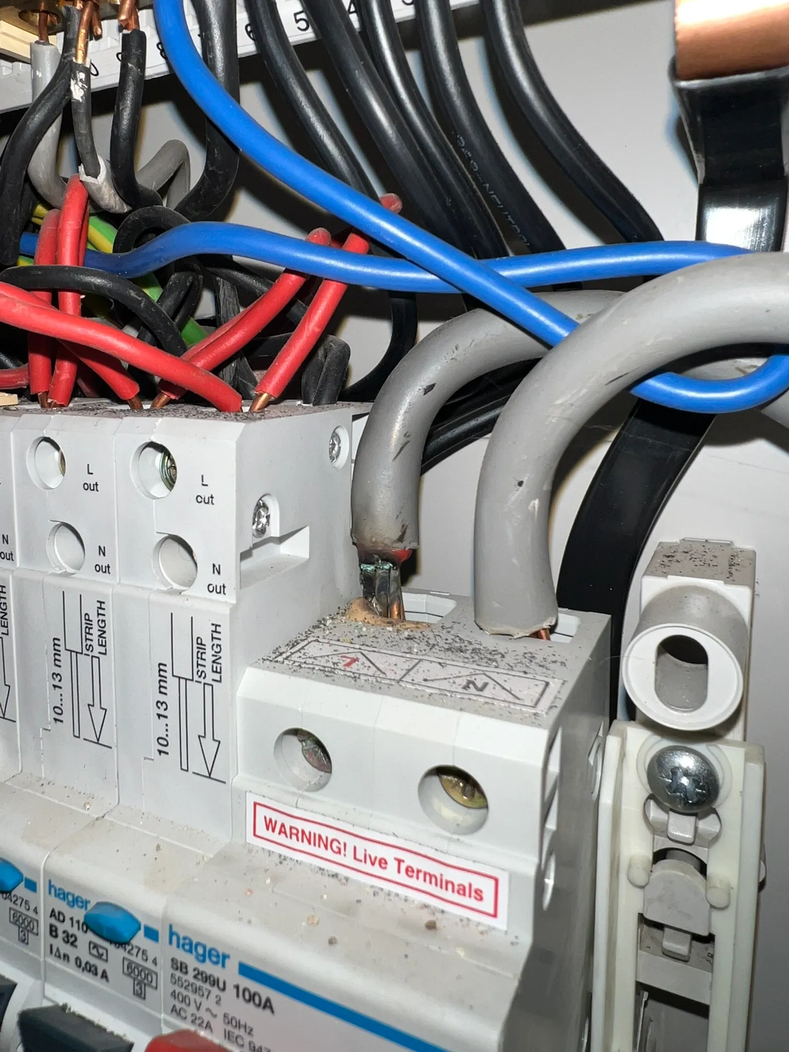 Close-up of a consumer unit connection with discolouration around a large cable terminal