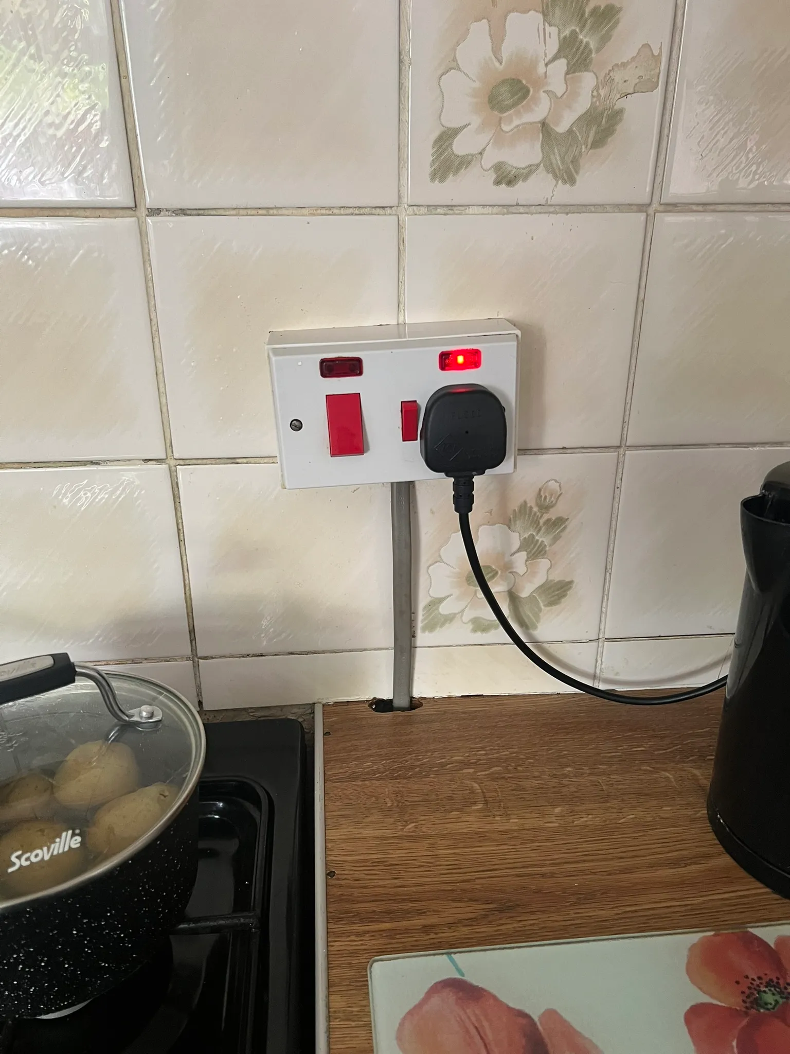 Cooker switch and socket beside a hob, with a cable running down through the worktop