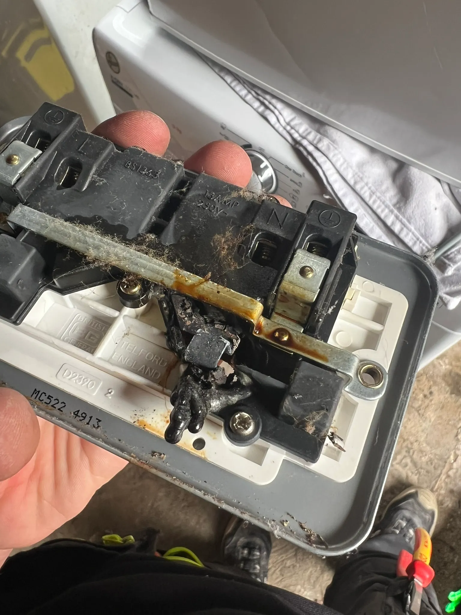 Rear of a removed double socket showing blackened and deformed material around a connection