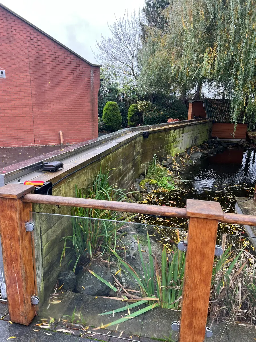 Daytime view across the garden pond, with tools on the wall