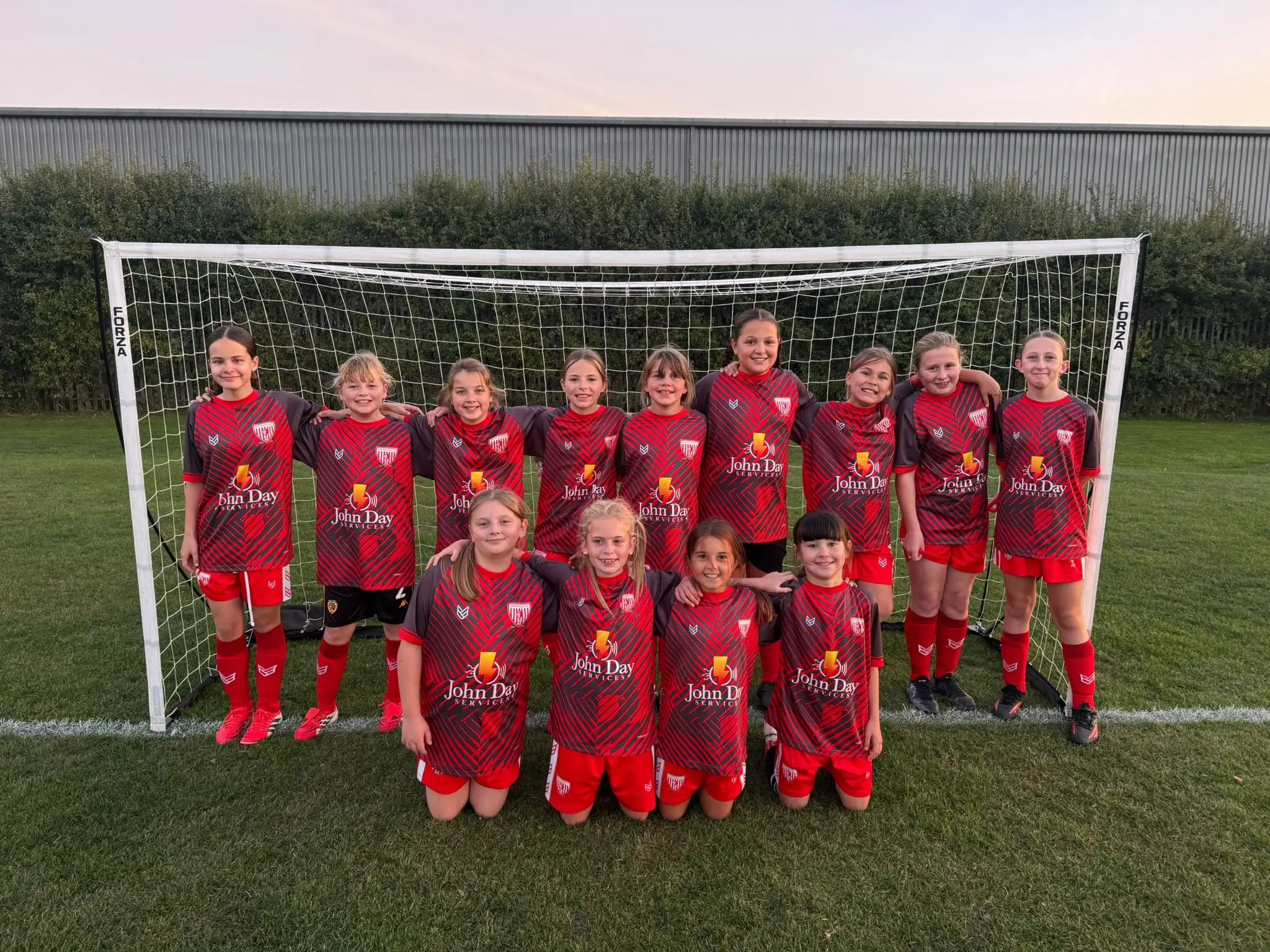 the Springhead Falcons girls’ football team in their red John Day Services sponsored kit