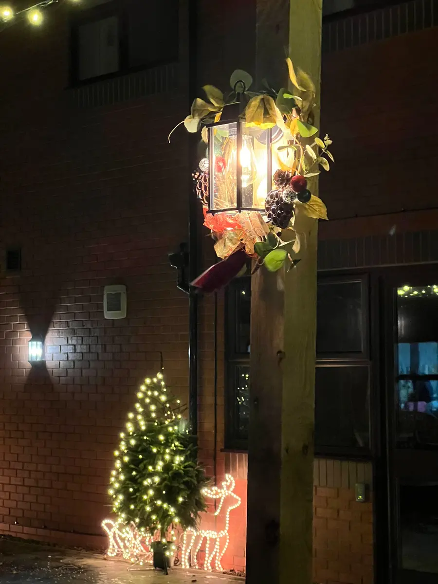 Glowing lantern on a wooden post with illuminated decorations behind it