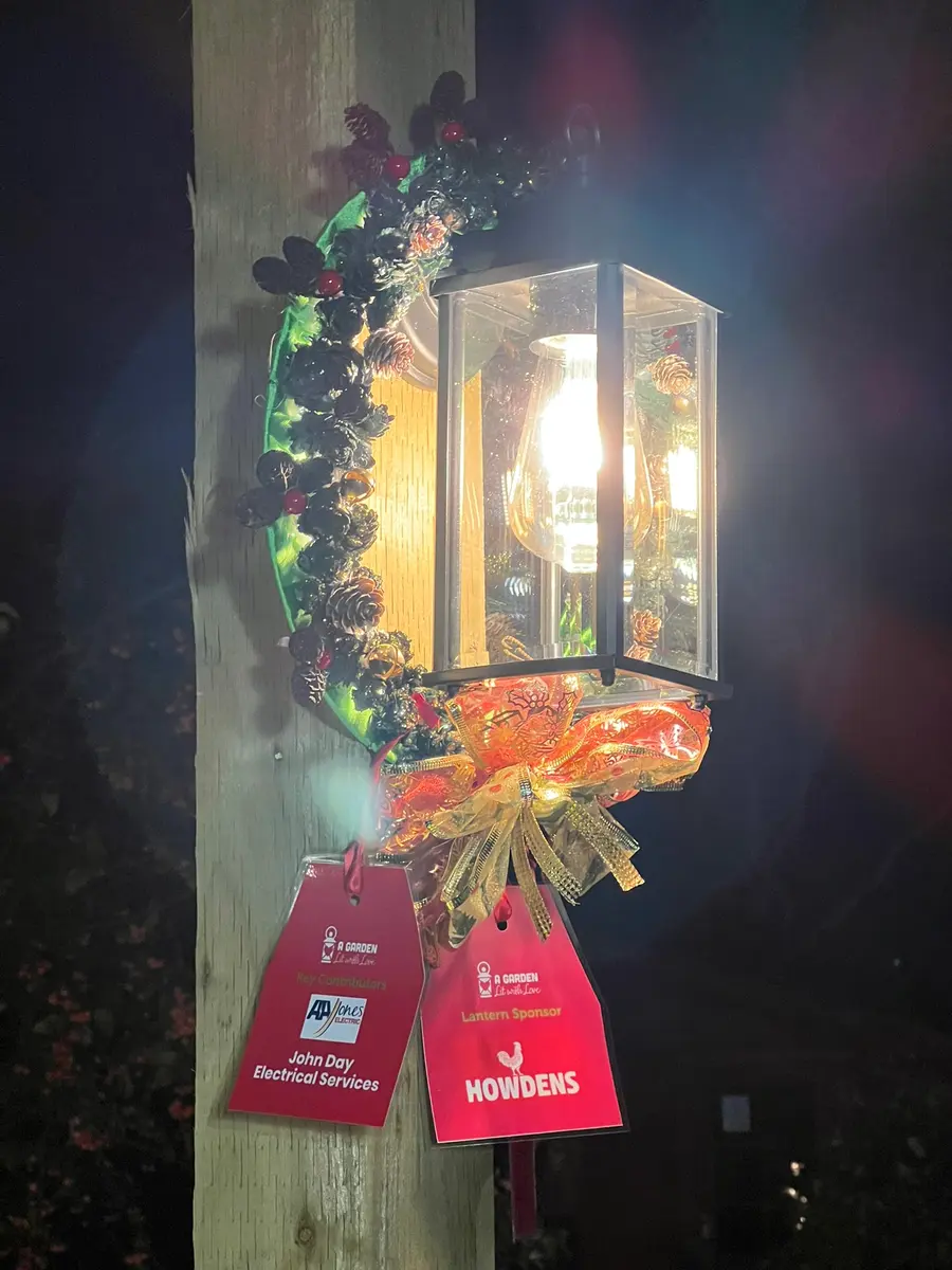 Illuminated lantern decorated with foliage and red dedication tags