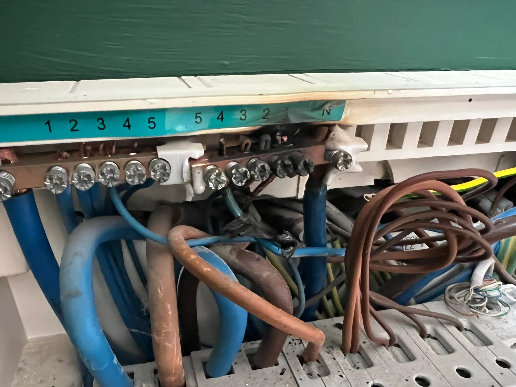 Inside a consumer unit, blackened terminals and charred insulation along part of the neutral bar