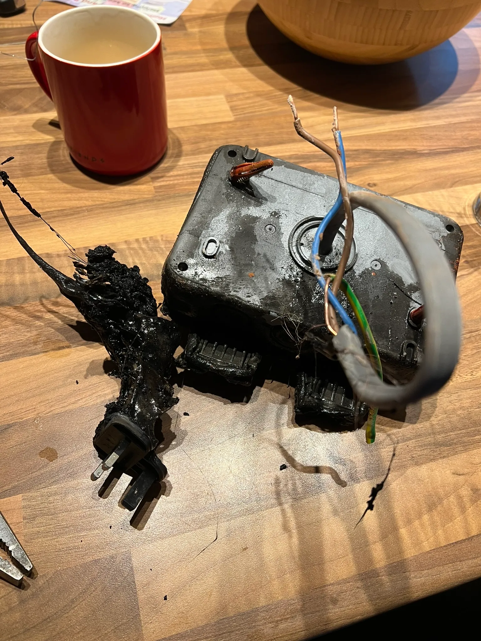 Charred socket enclosure, plug and wiring laid out after the fire
