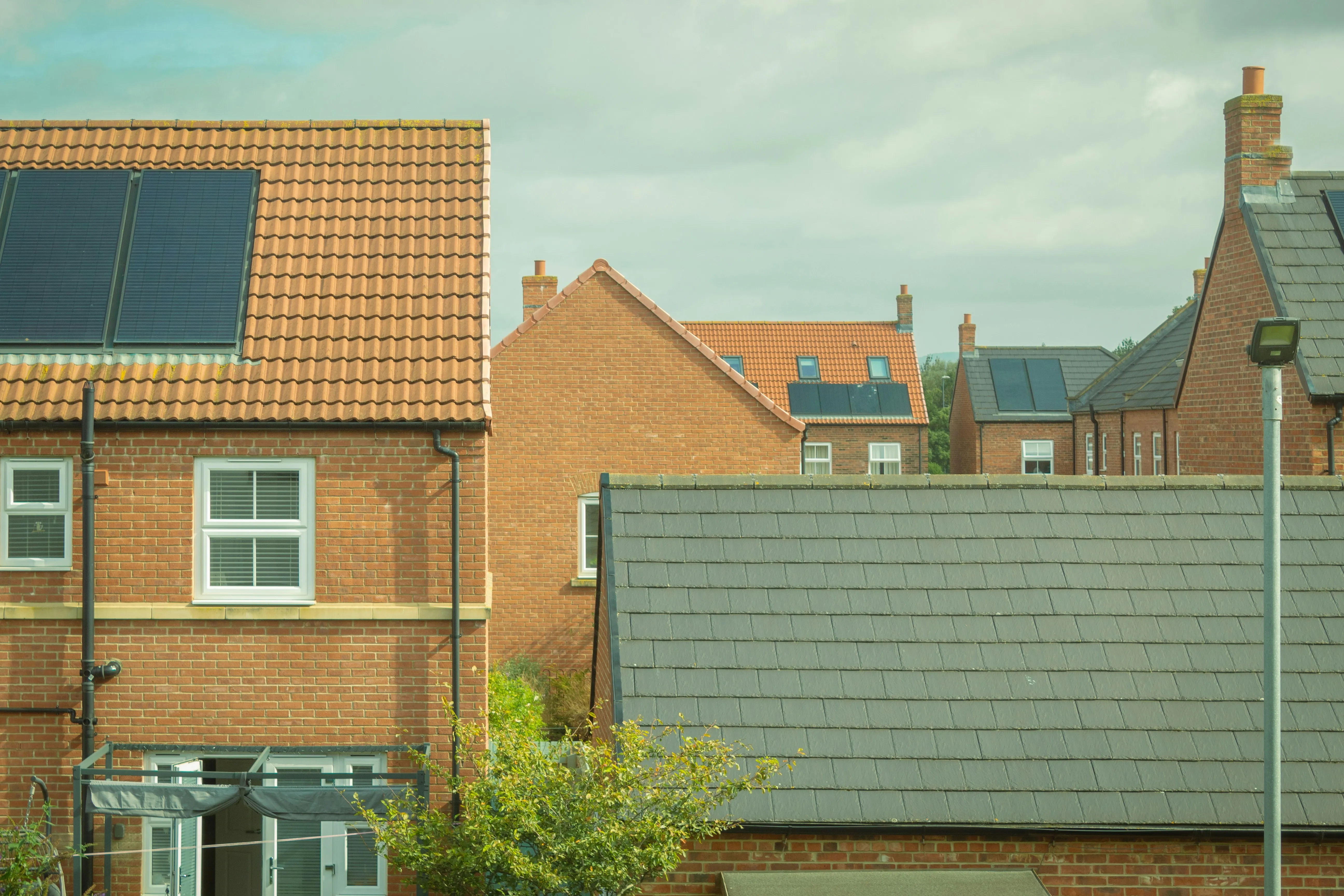 Brick houses with tiled roofs, chimneys and rooftop solar panels